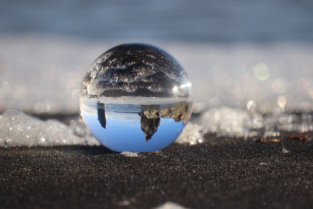 clear glass ball on black sand