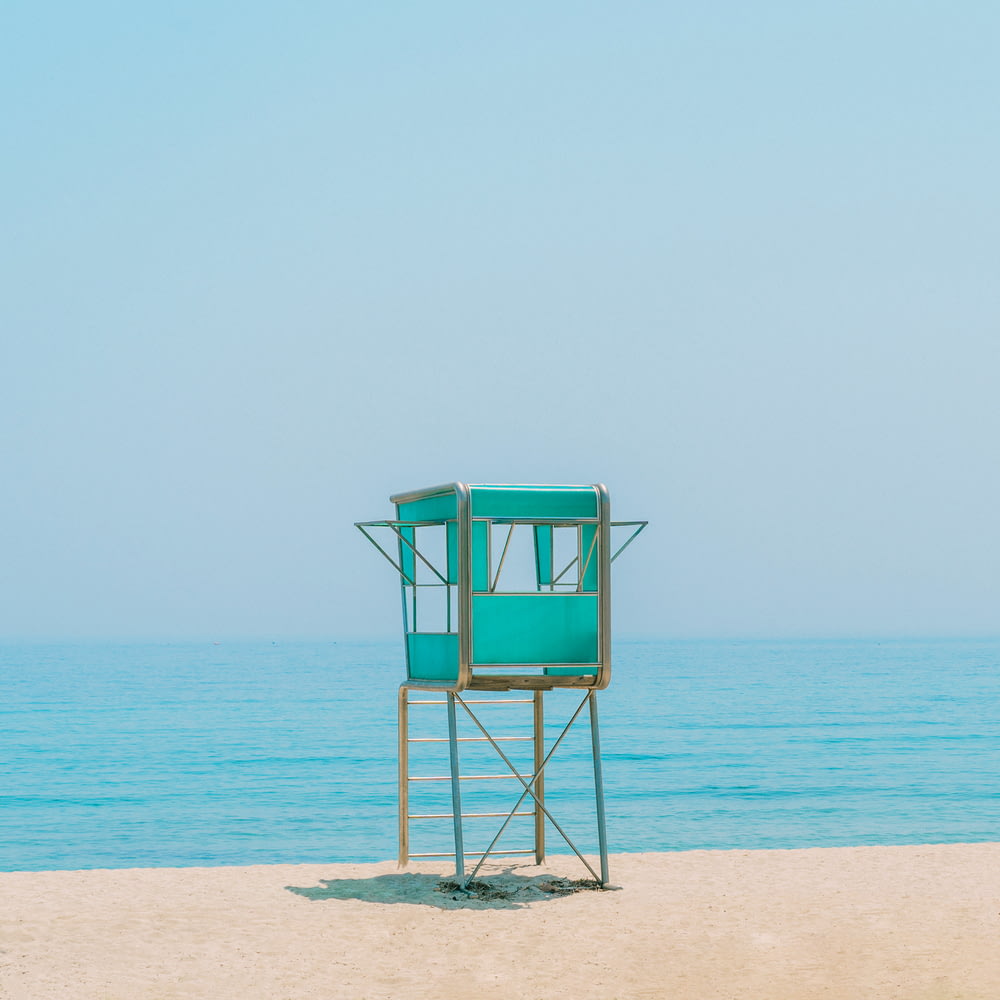blue wooden lifeguard chair on beach during daytime