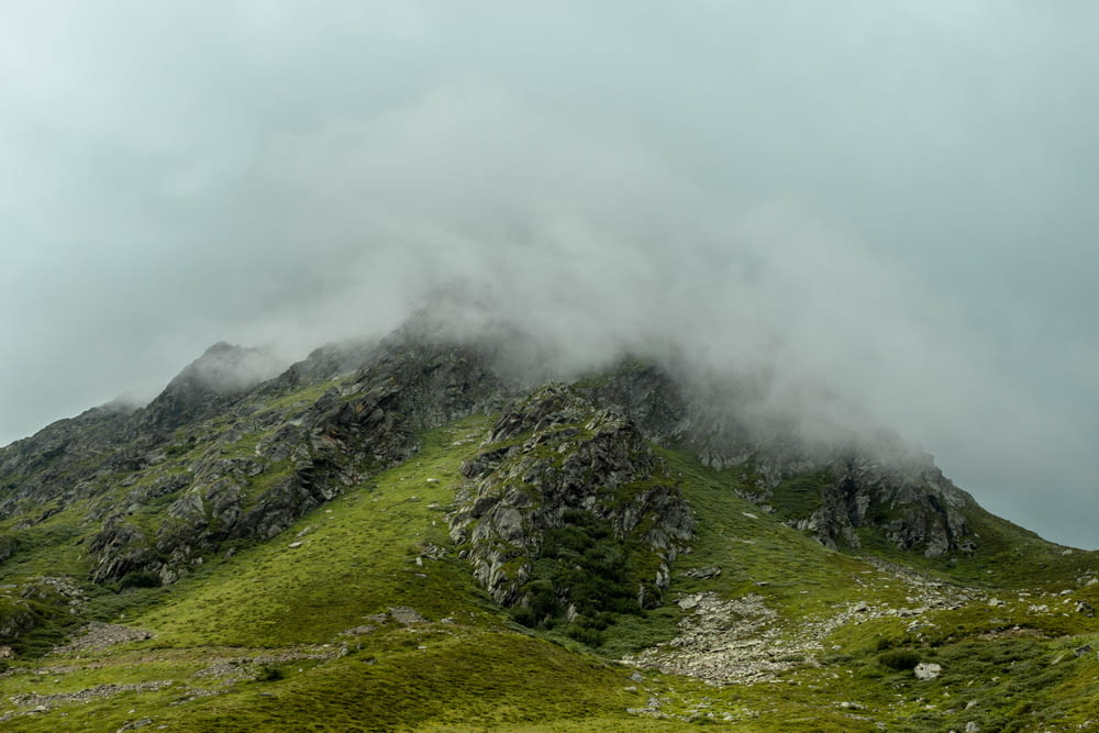 昼間の白い雲の下の緑の山