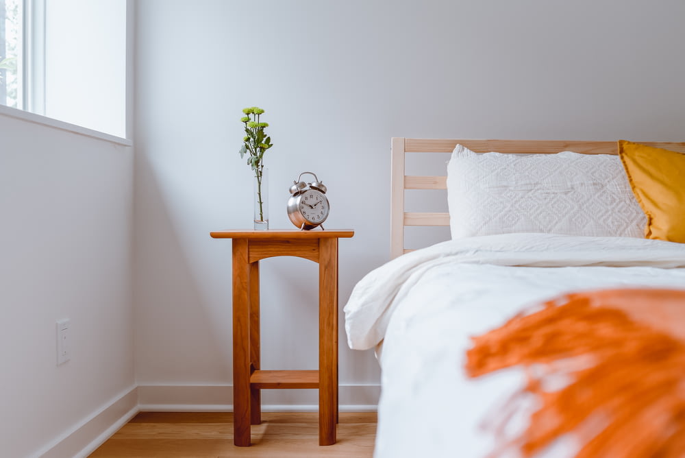mesa de madeira marrom com roupa de cama floral branca e laranja
