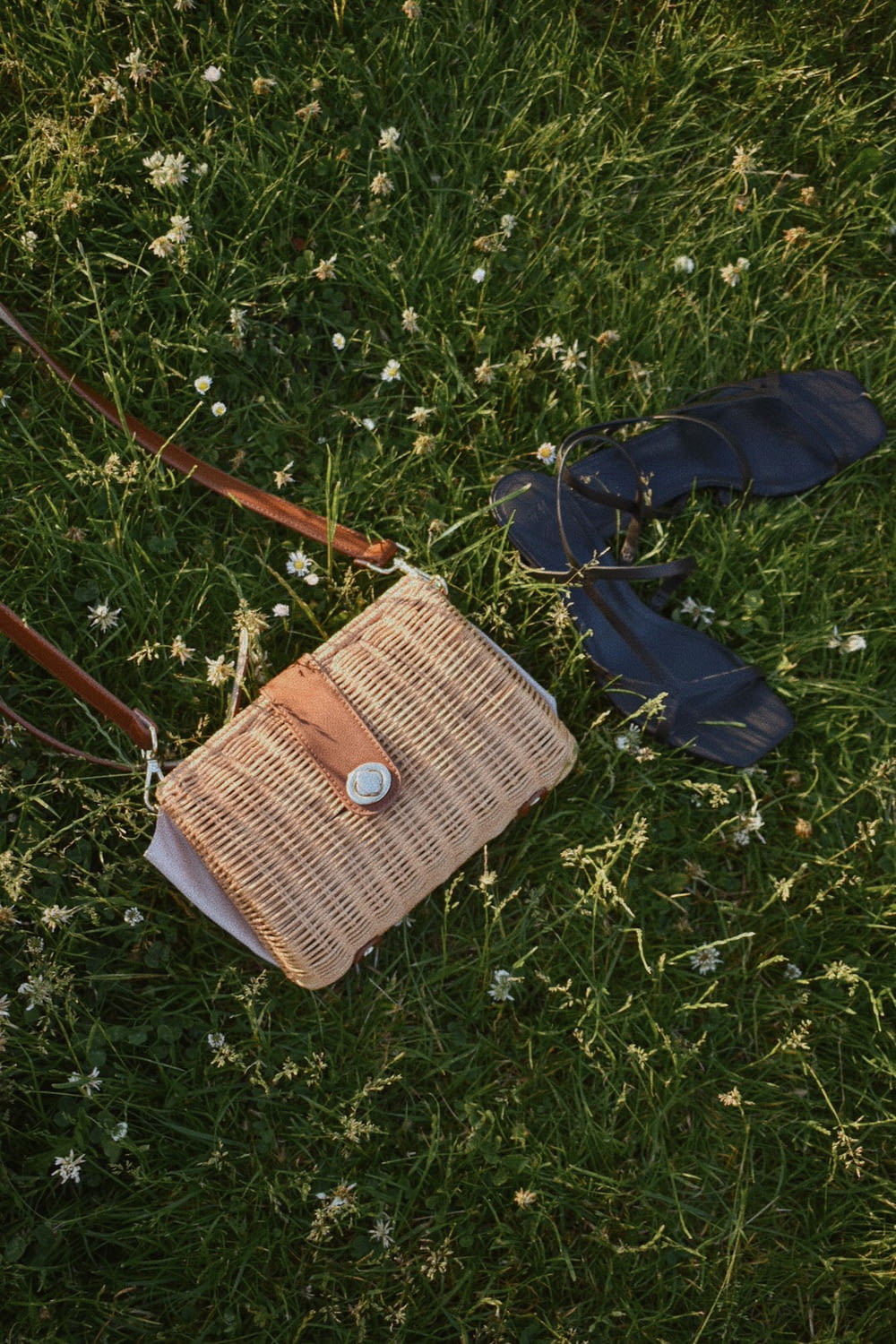 brown leather sling bag on green grass