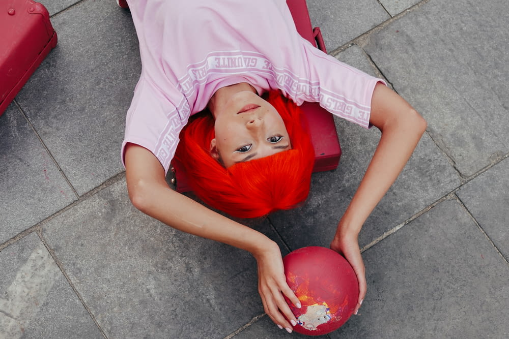 girl in pink shirt lying on red inflatable ball