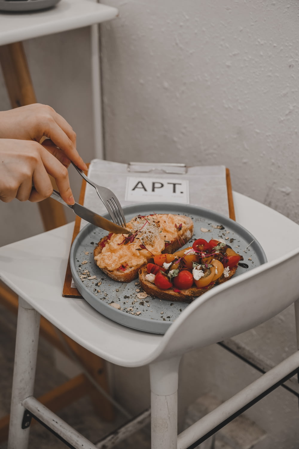 스테인레스 스틸 포크와 흰색 세라믹 접시에 토마토를 자르는 칼을 들고 있는 사람