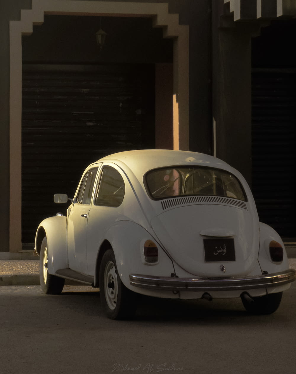 white volkswagen beetle parked beside brown wooden wall