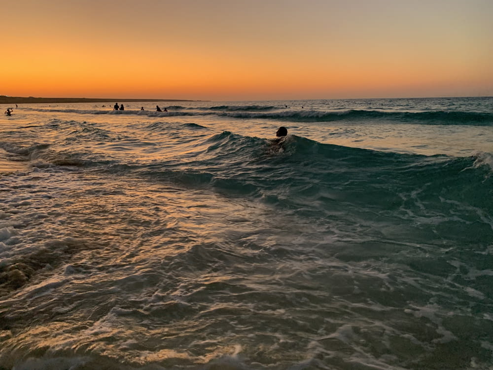 man surfing on sea waves during sunset