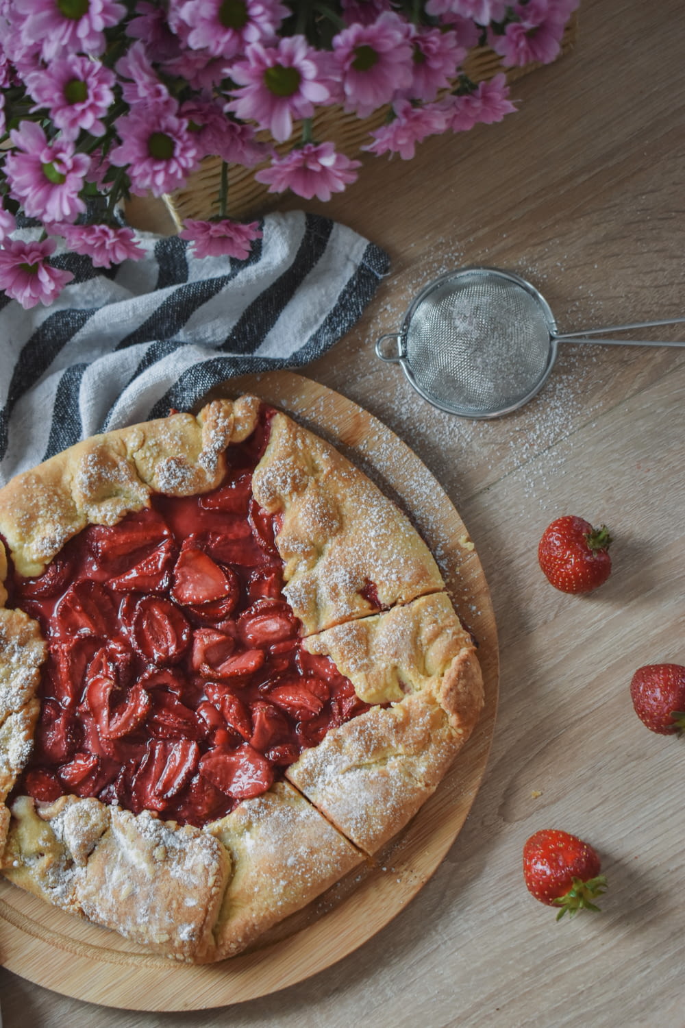 pizza with red and white sliced strawberries on brown wooden round tray