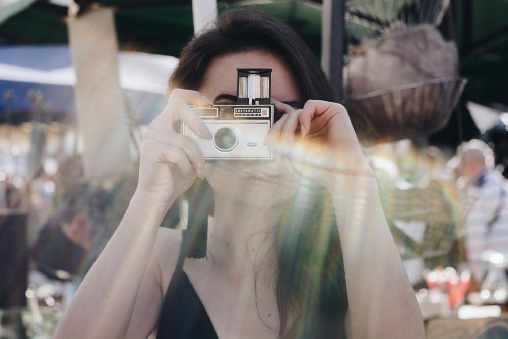 woman holding silver point and shoot camera