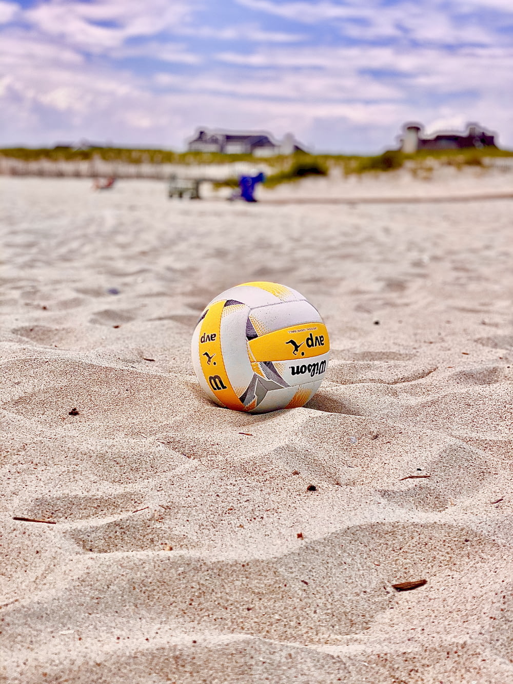 yellow and white volleyball on white sand during daytime