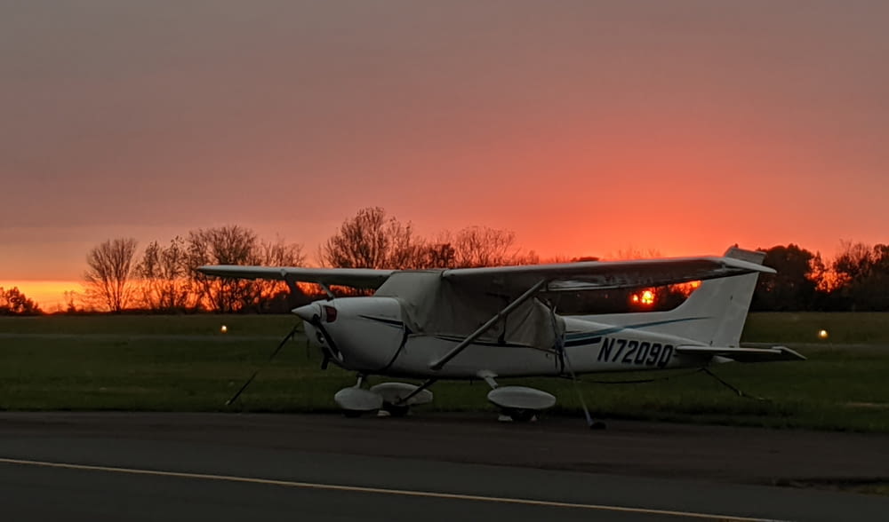 avião branco e vermelho no campo durante o pôr do sol