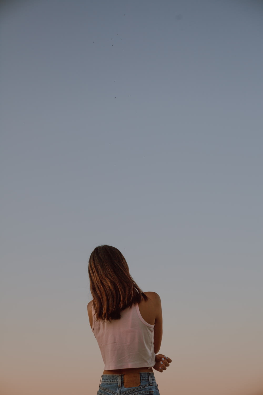 woman in white tank top looking at the sky during daytime