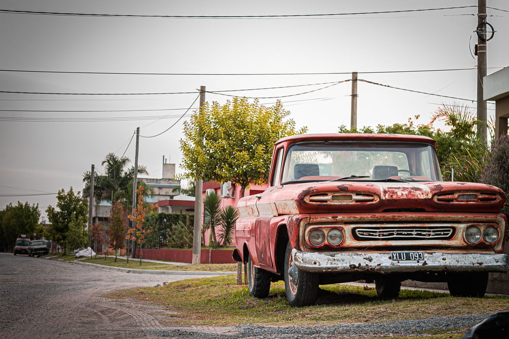 red chevrolet single cab pickup truck parked on the side of the road during daytime