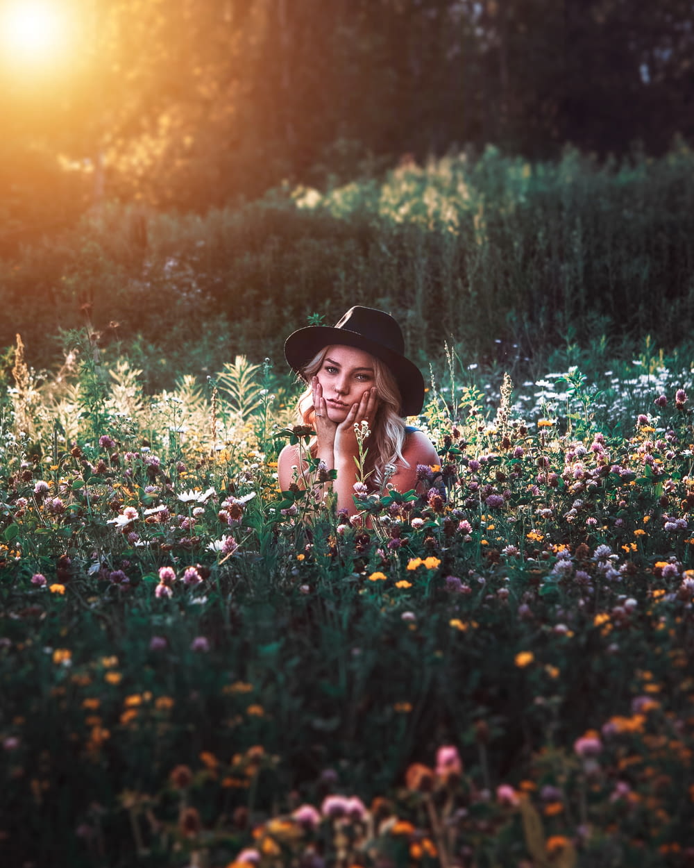 woman in black hat on flower field during daytime