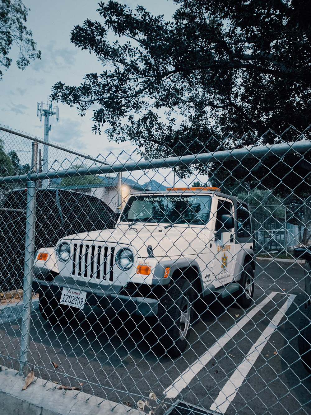 Jeep Wrangler bianca e nera parcheggiata accanto alla recinzione metallica grigia
