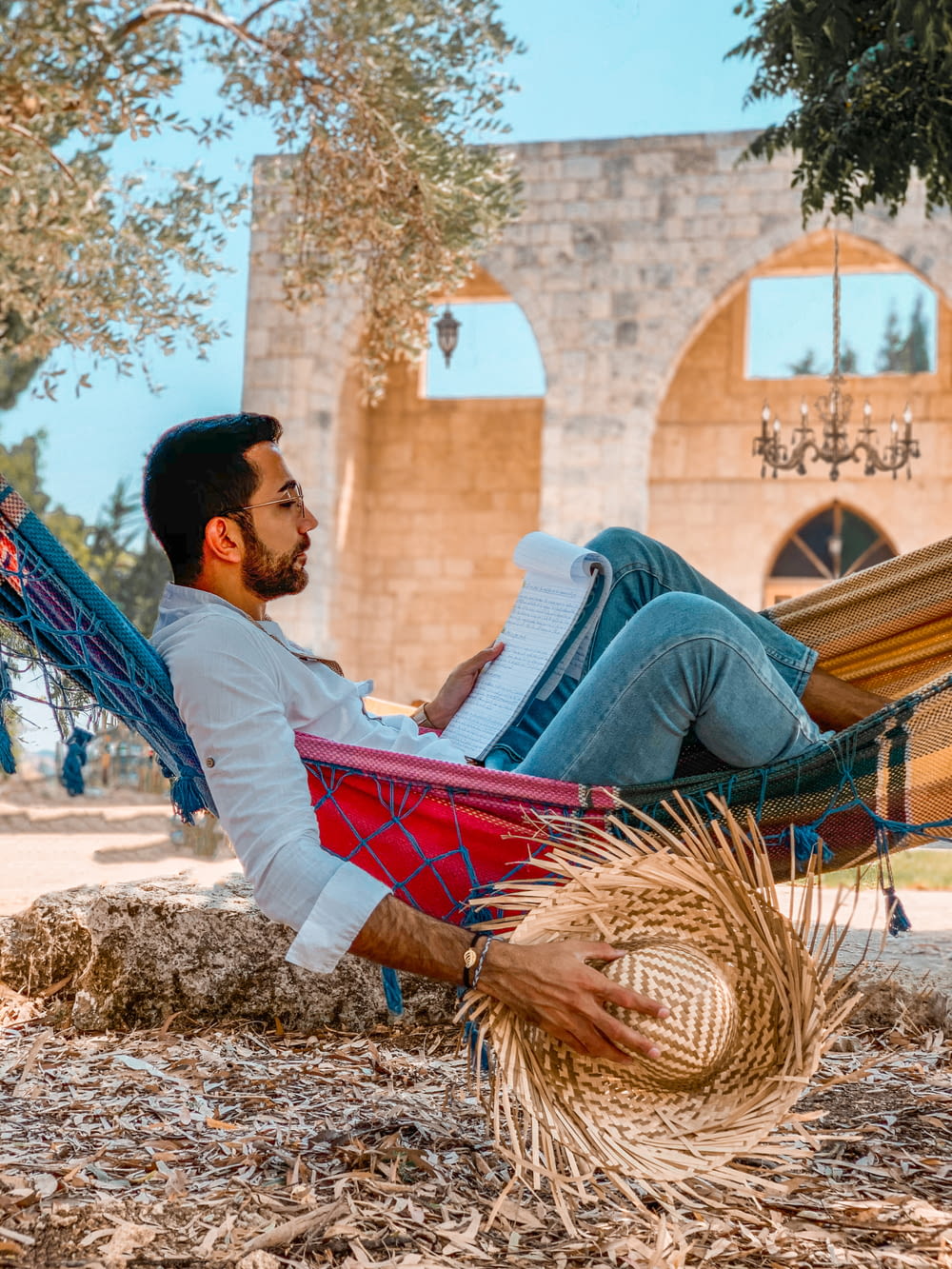 man in white shirt and blue denim jeans sitting on hammock