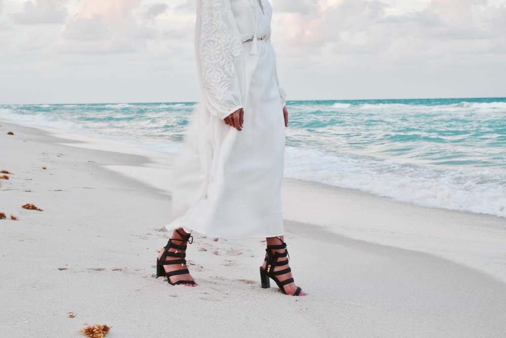 woman in white dress standing on beach during daytime
