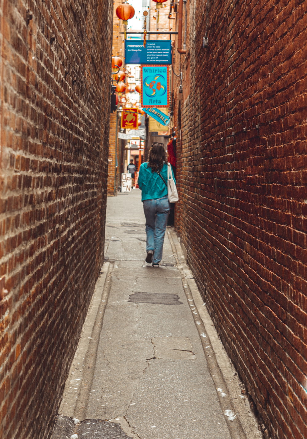 woman in blue denim jeans walking on sidewalk during daytime