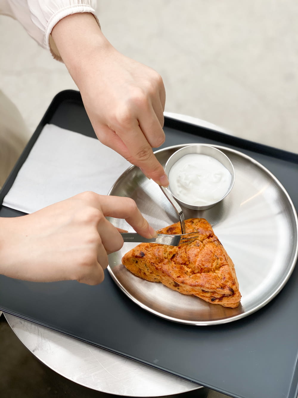 person holding stainless steel spoon and fork on white ceramic plate