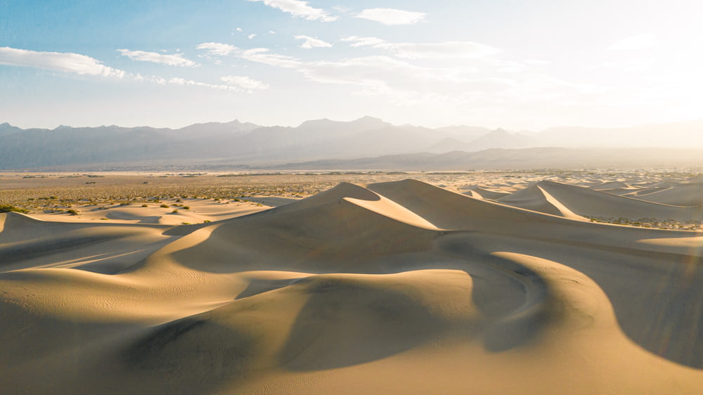 campo de areia marrom sob o céu branco durante o dia