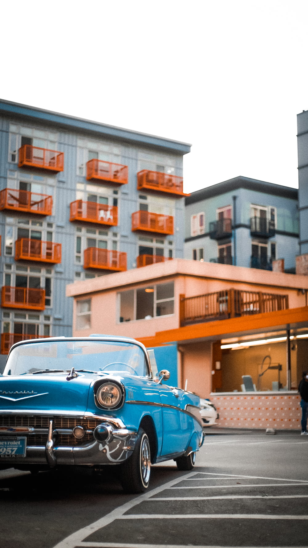 昼間、茶色の建物の近くに駐車された青い車