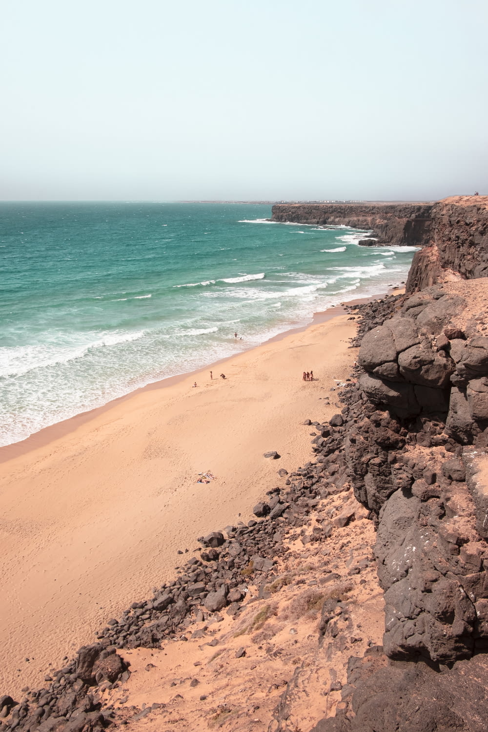 Brauner Sandstrand mit braunem Sand und blauem Meerwasser tagsüber