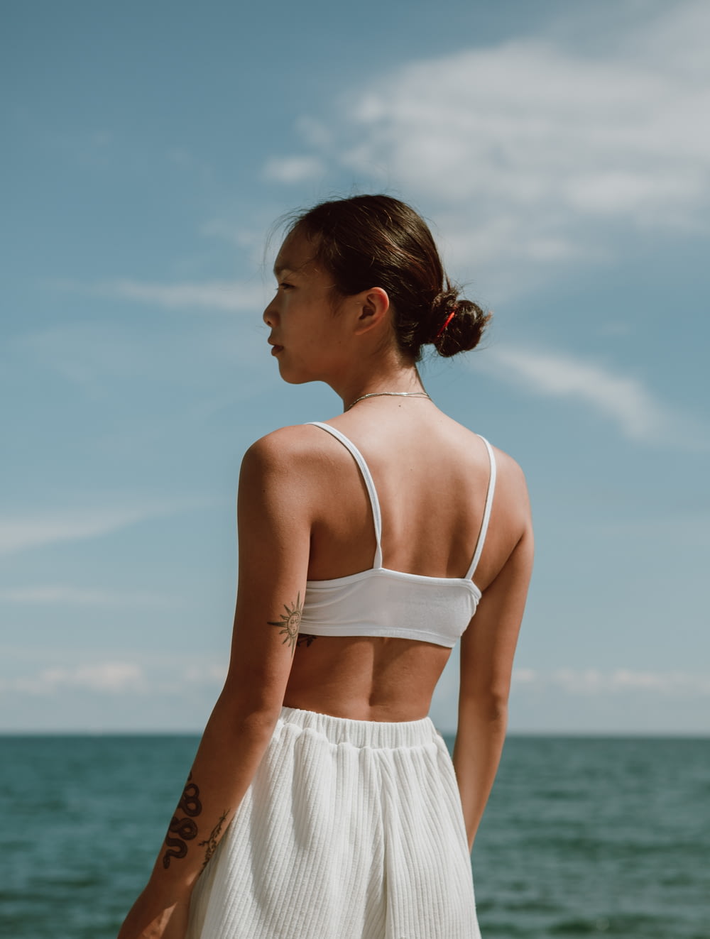 Femme en haut à bretelles spaghetti blanc et jupe blanche debout sur la plage pendant la journée