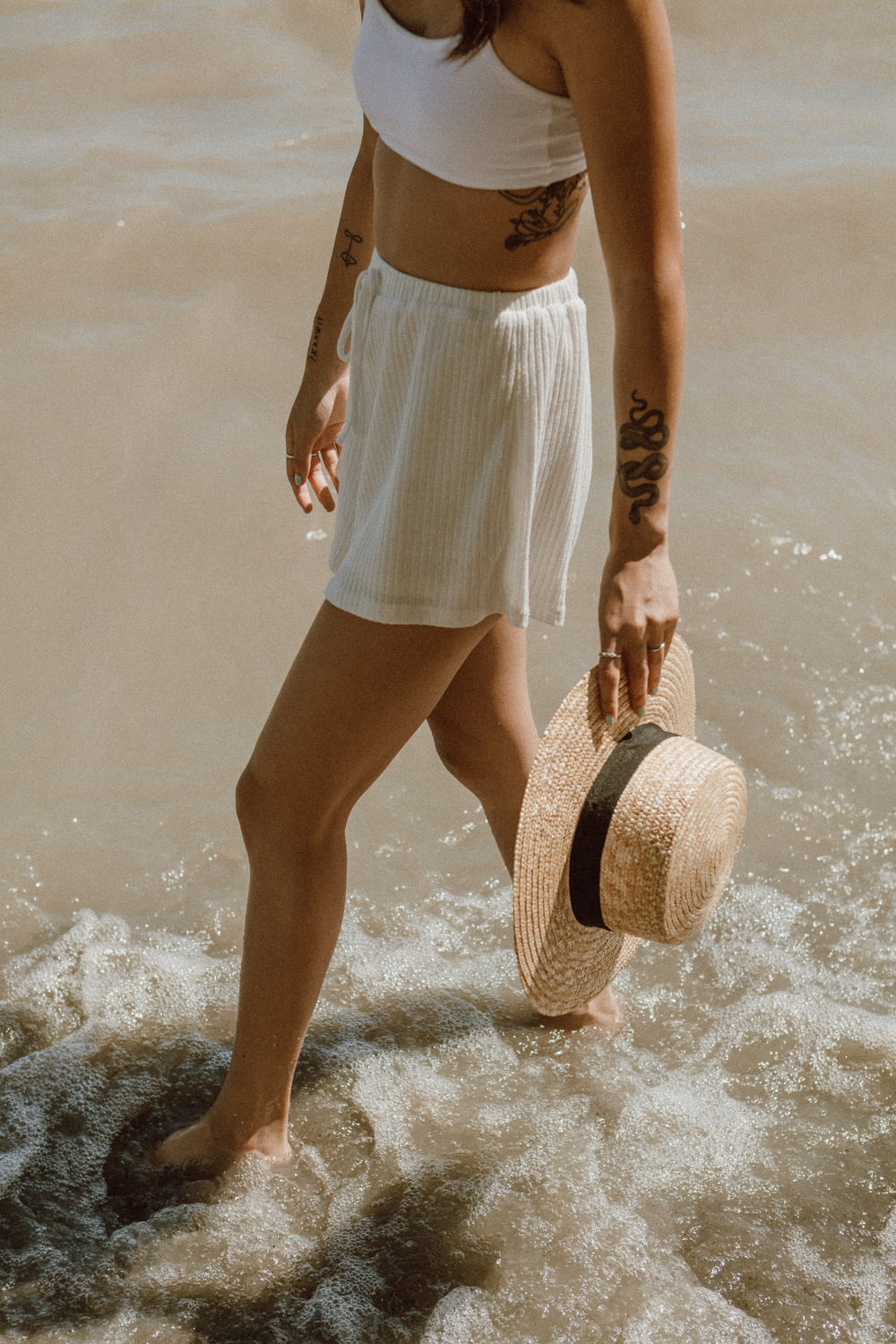 woman in white and brown stripe skirt and brown sun hat standing on water during daytime