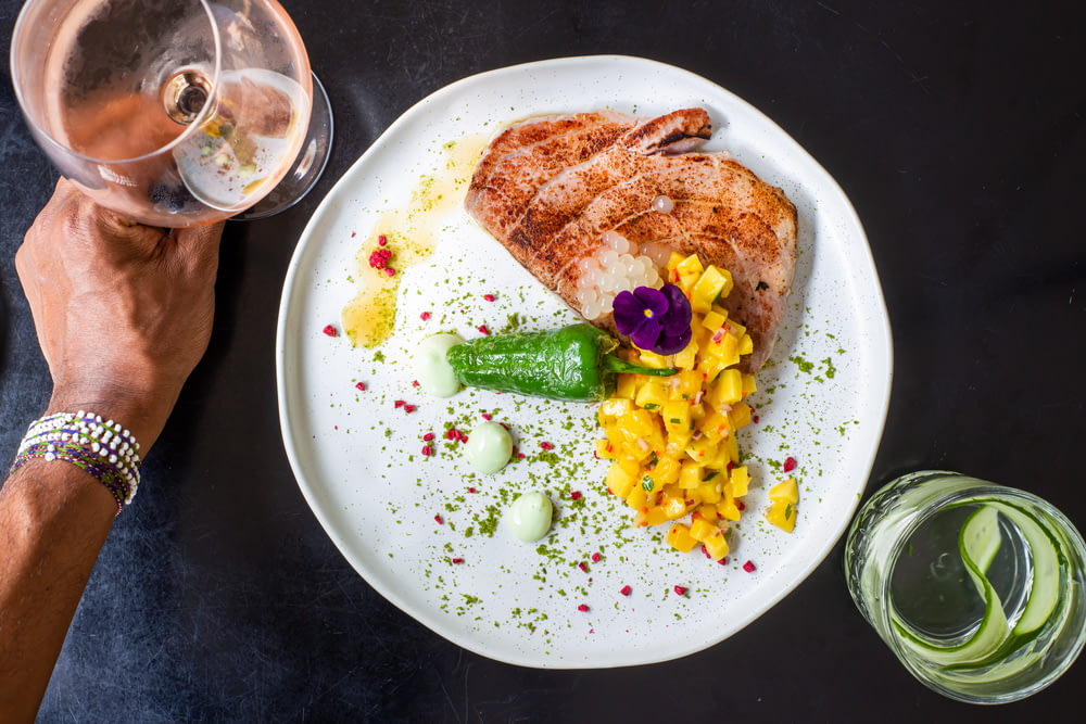 fried fish with corn and green vegetable on white ceramic plate