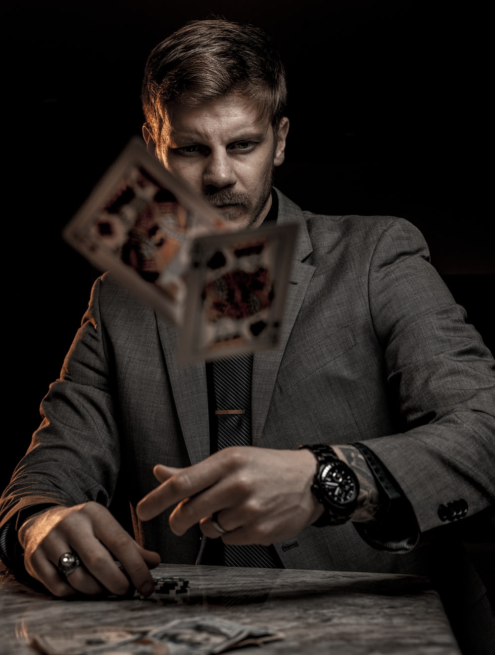 man in gray suit jacket holding jack of diamonds playing card