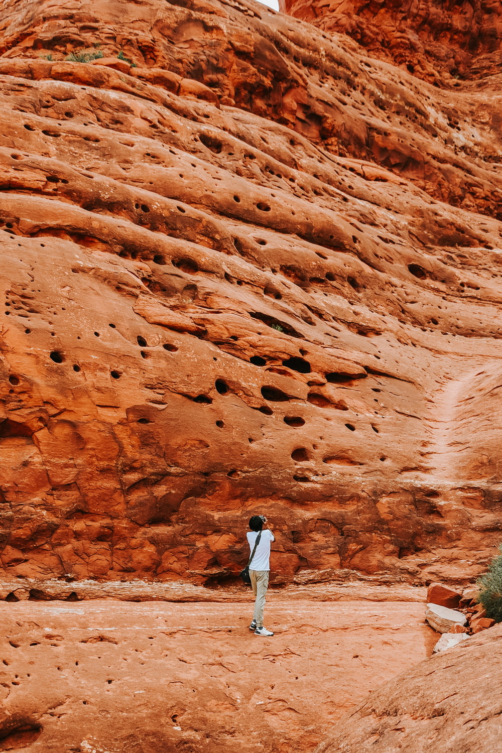 woman in white long sleeve shirt and white pants standing on brown rock formation during daytime