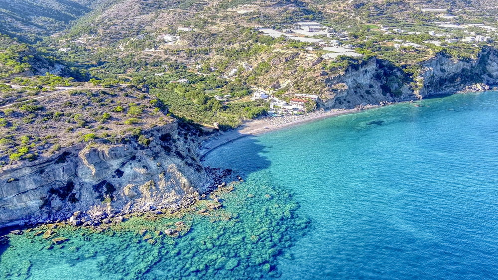 vista aérea da montanha verde e cinza ao lado do mar azul durante o dia