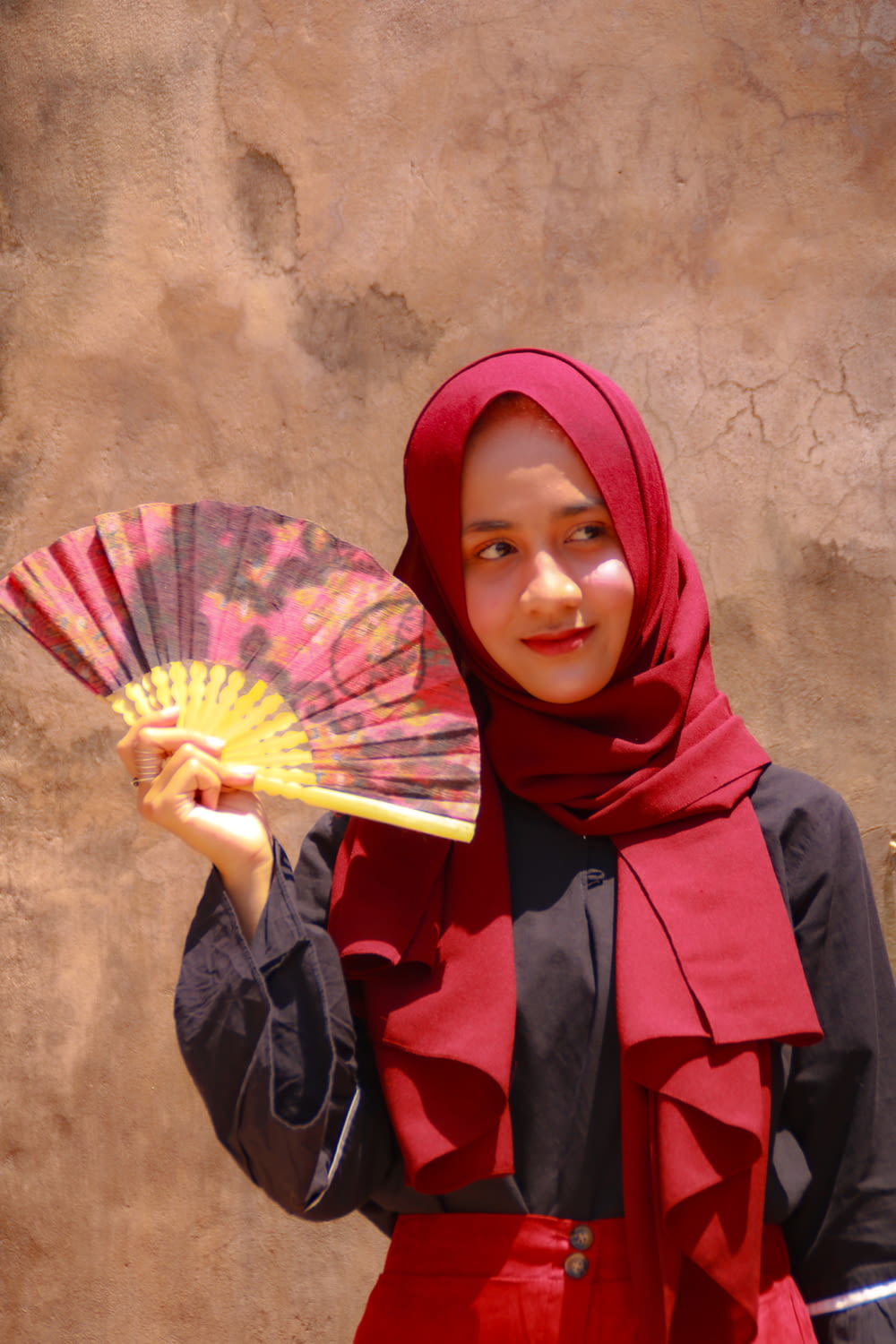 woman in red hijab holding yellow hand fan