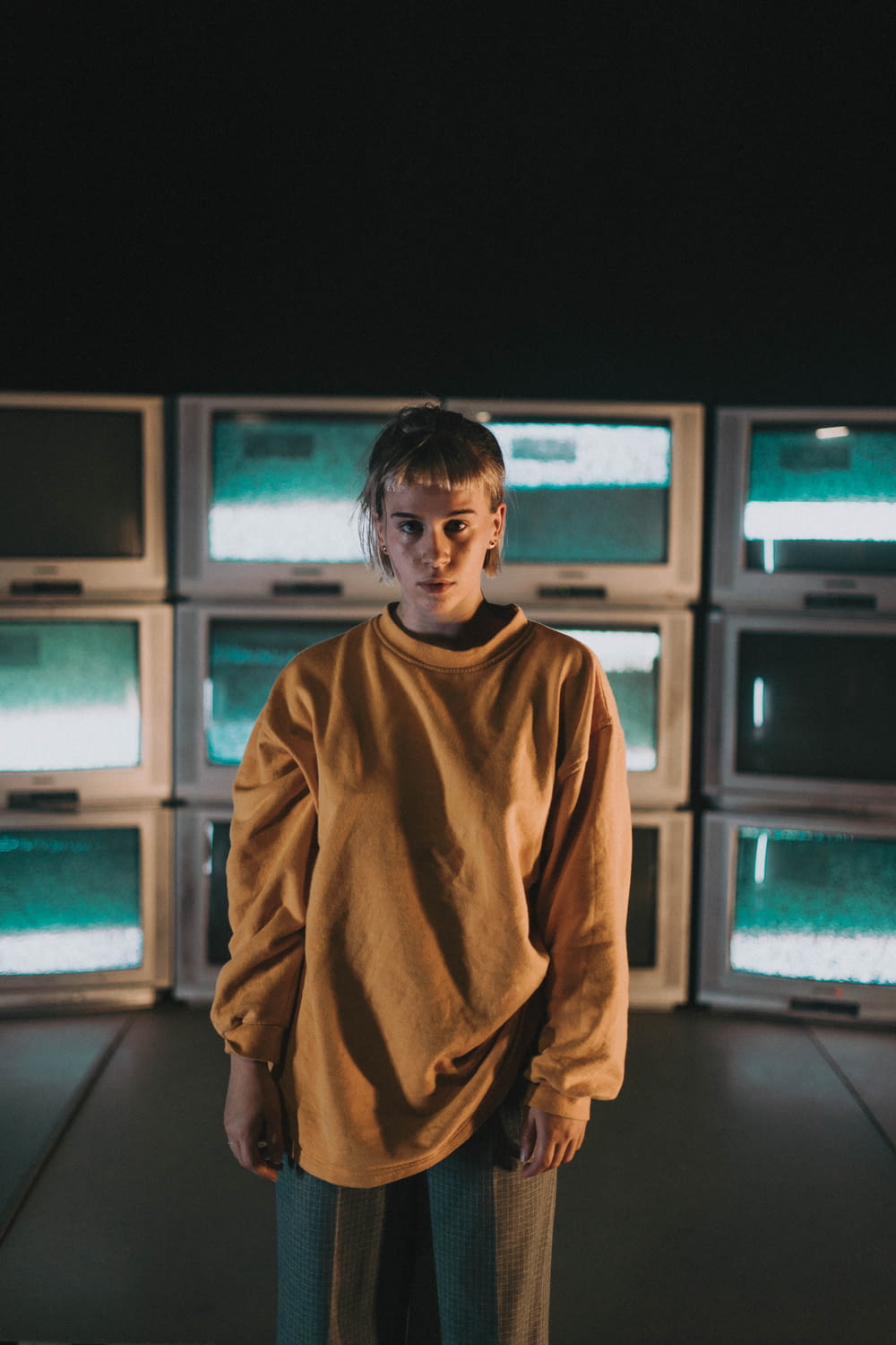 boy in brown turtleneck sweater standing near black crt tv