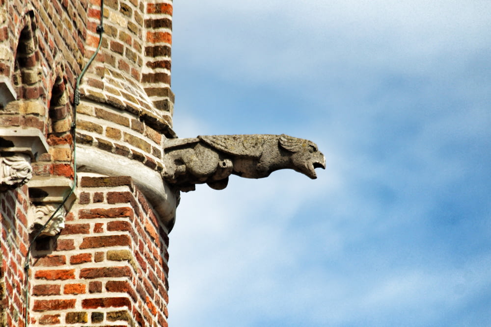 Graue Betonvogelstatue auf dem Dach eines braunen Betongebäudes