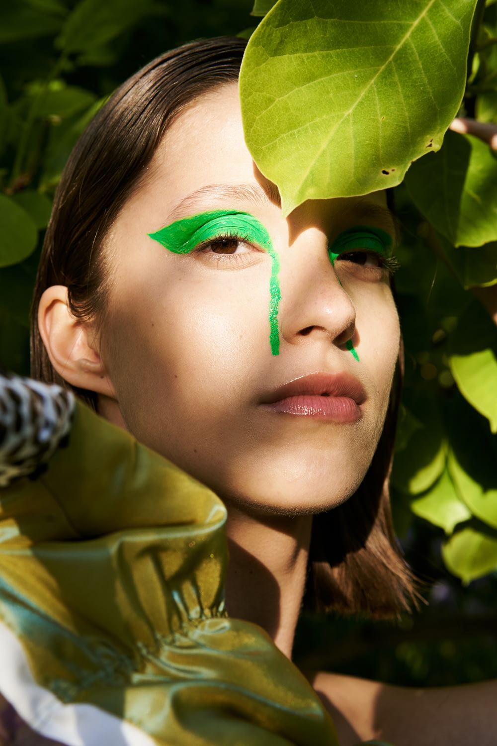 a woman with green makeup and a green leaf