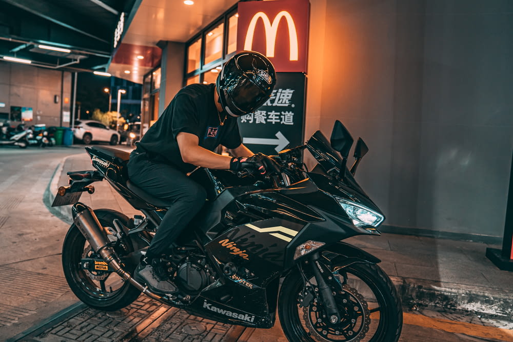 hombre con camiseta negra montando motocicleta negra