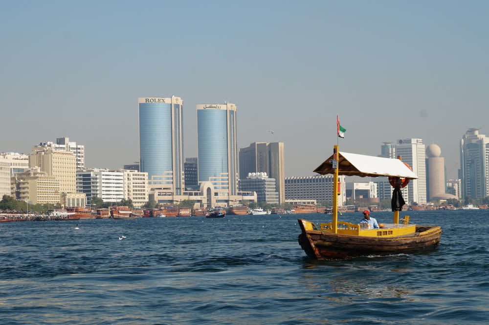 brown boat on body of water near city buildings during daytime