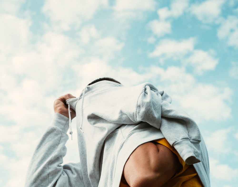 woman in white hoodie covering her face with white textile