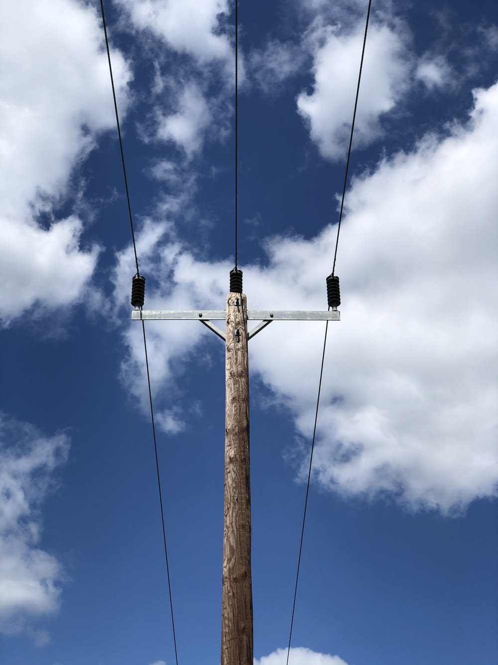brown wooden electric post under blue sky