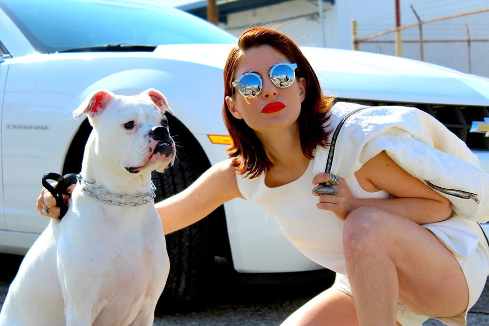 woman in white tank top wearing sunglasses sitting on white car during daytime