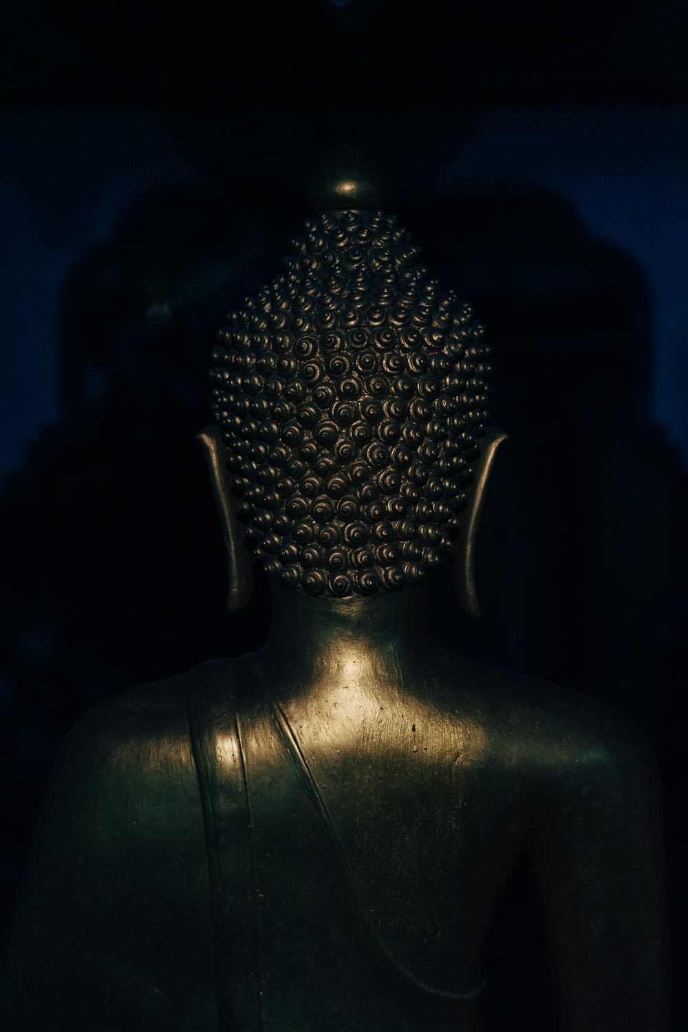 silver buddha statue in dark room