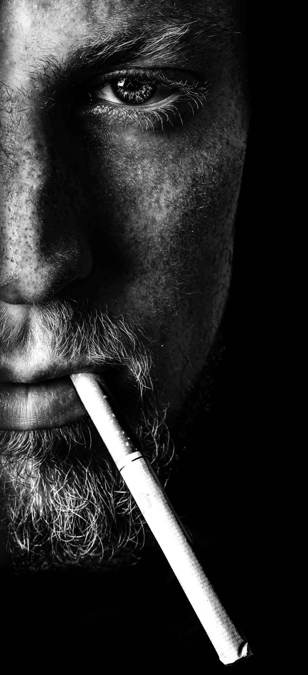 uomo che fuma sigaretta in fotografia in scala di grigi