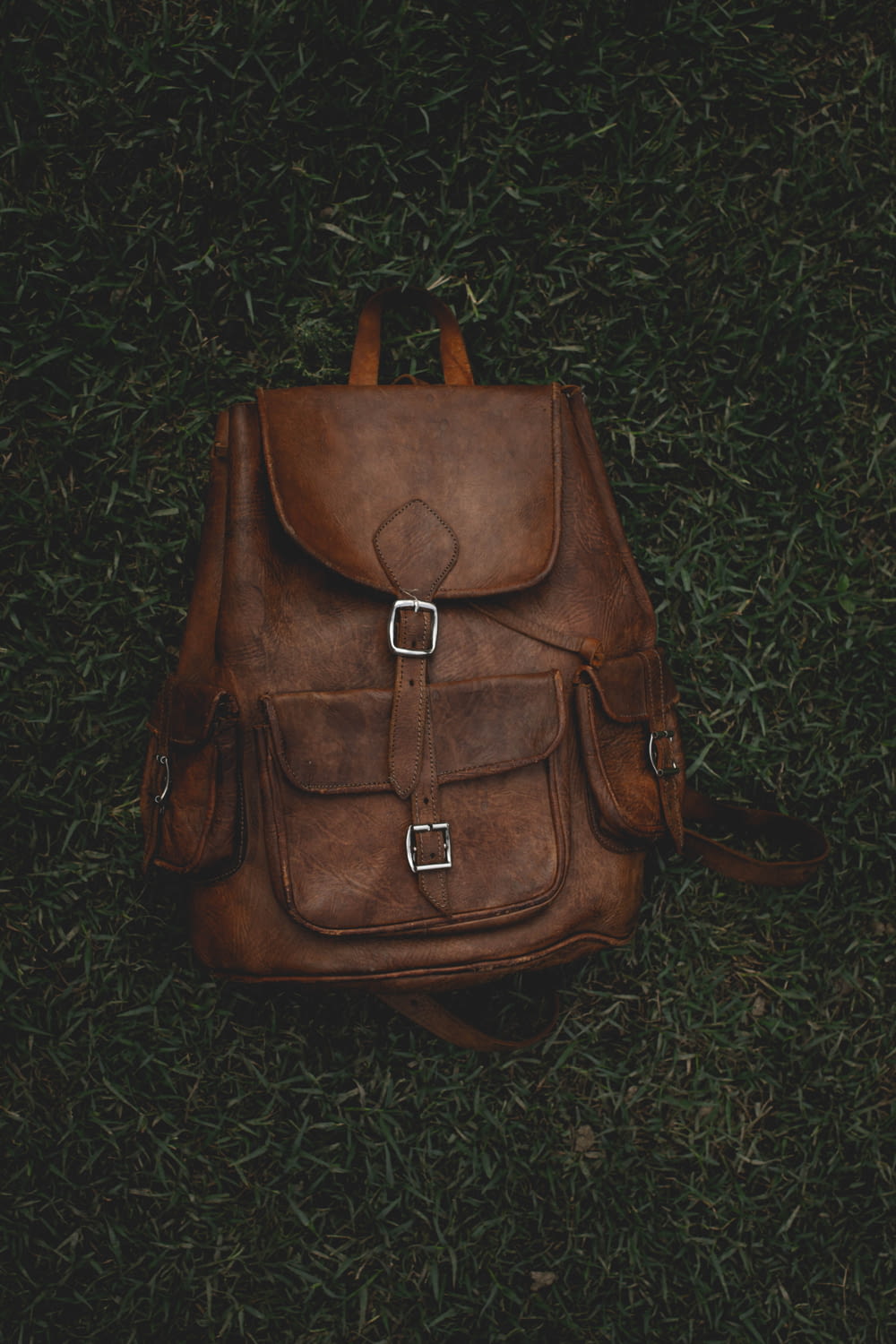 brown leather handbag on green textile