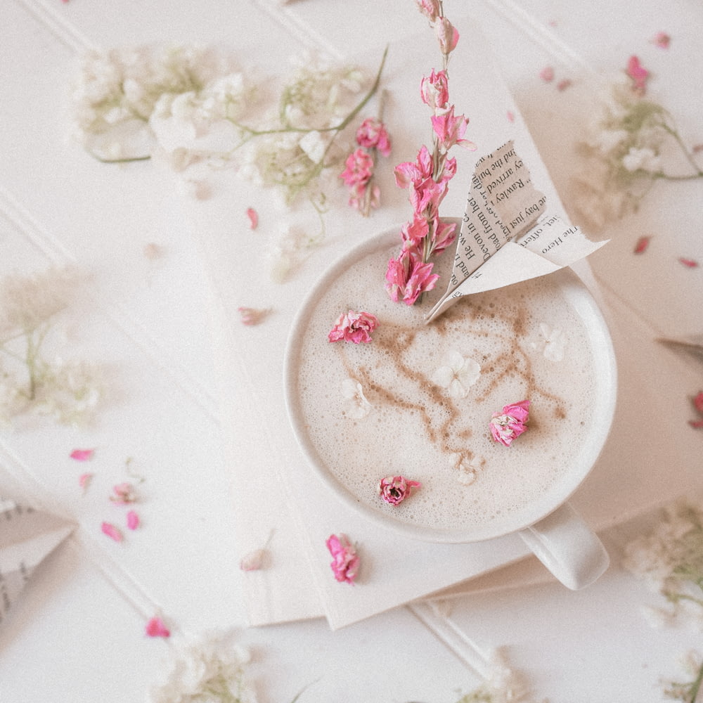 a cup of coffee with pink flowers on a table