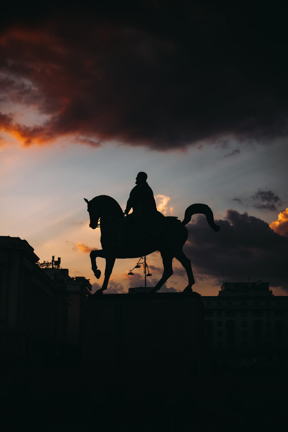 silhouette of man riding horse statue during sunset
