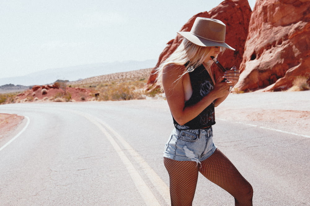 woman in black tank top and white denim shorts standing on road during daytime