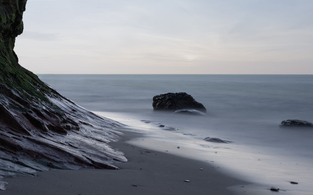 formazione rocciosa grigia sulla riva del mare durante il giorno