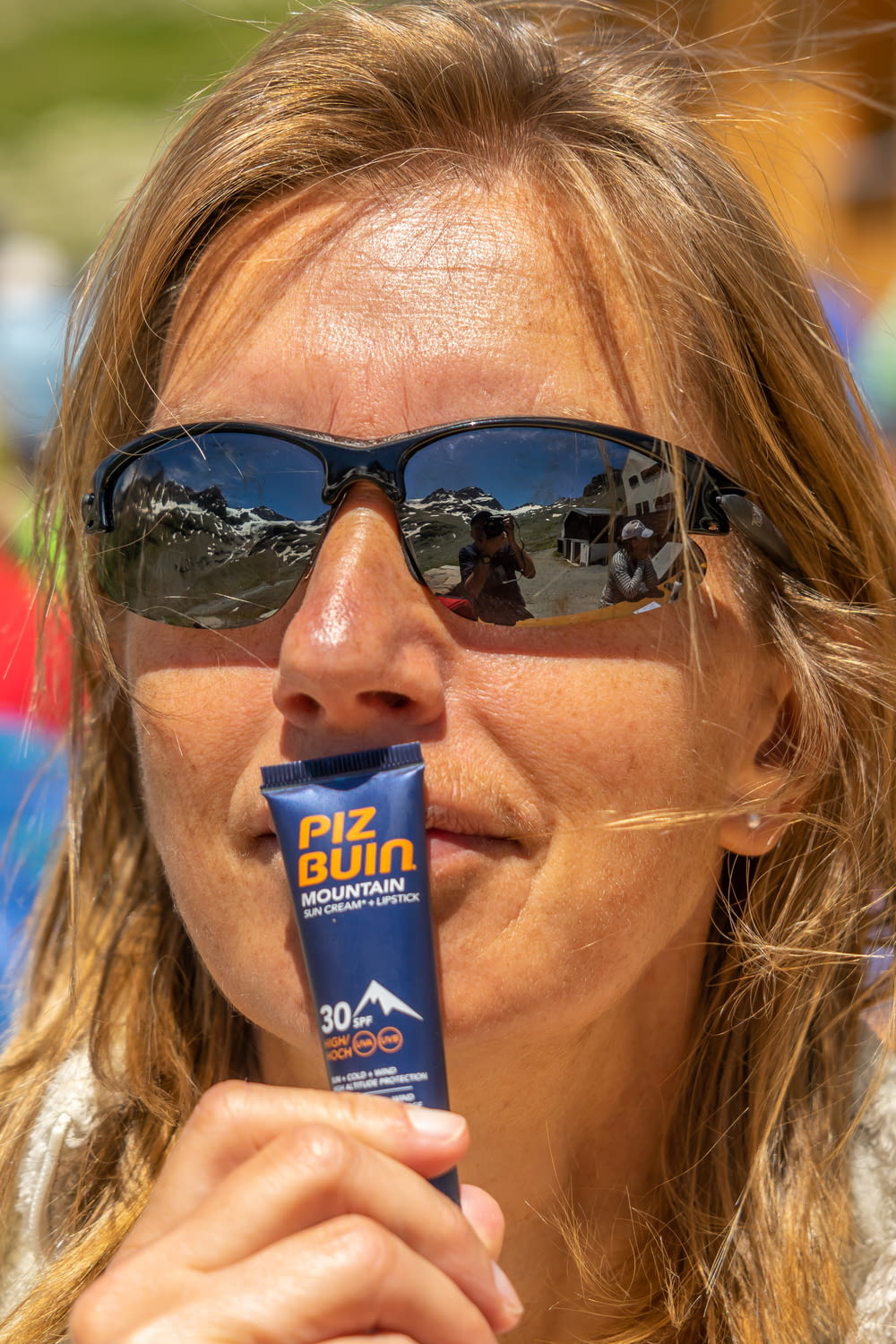woman in black sunglasses holding blue tube bottle
