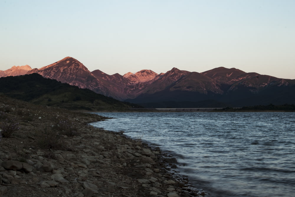 brown mountain near body of water during daytime