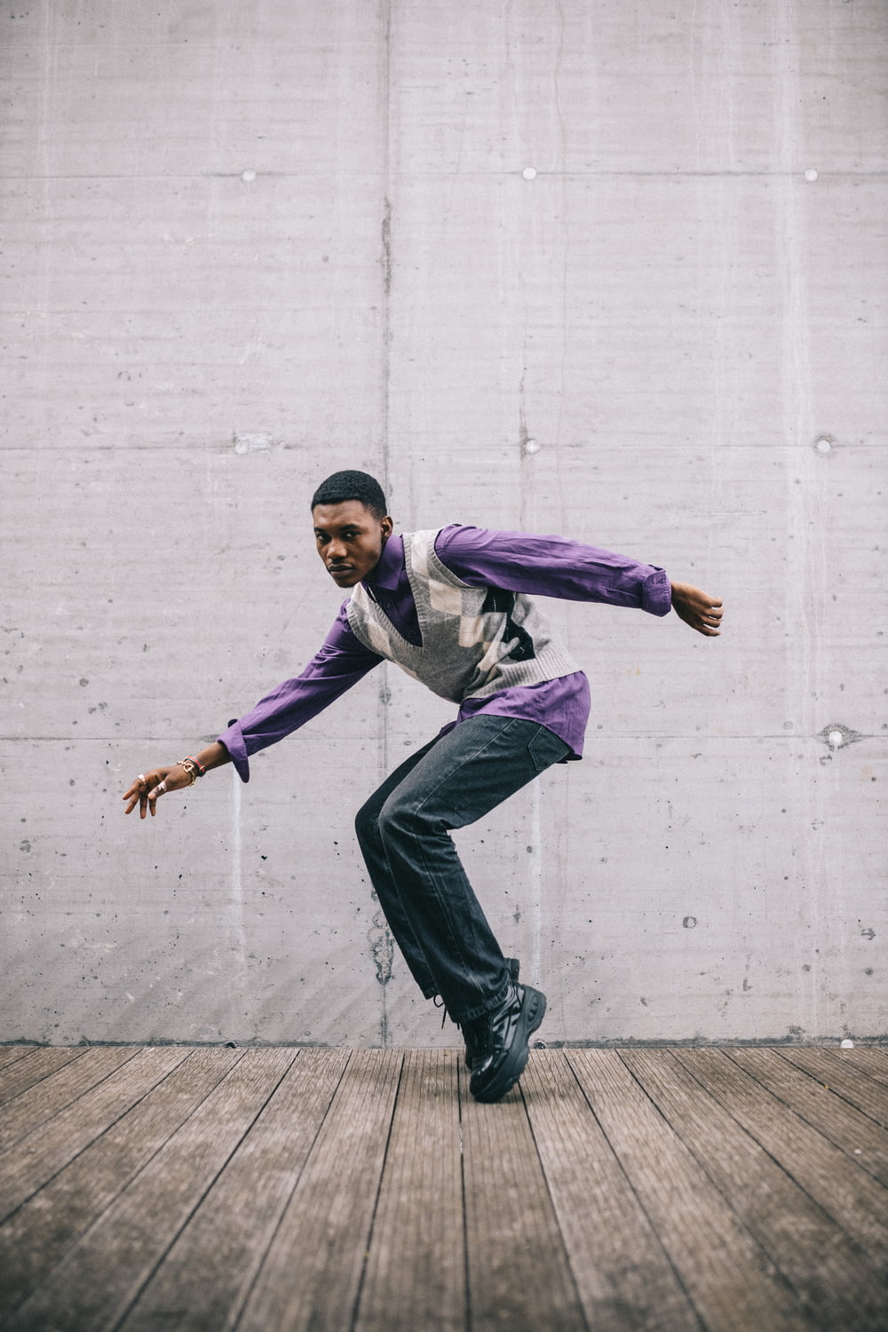 man in purple dress shirt and black pants jumping on gray concrete floor during daytime