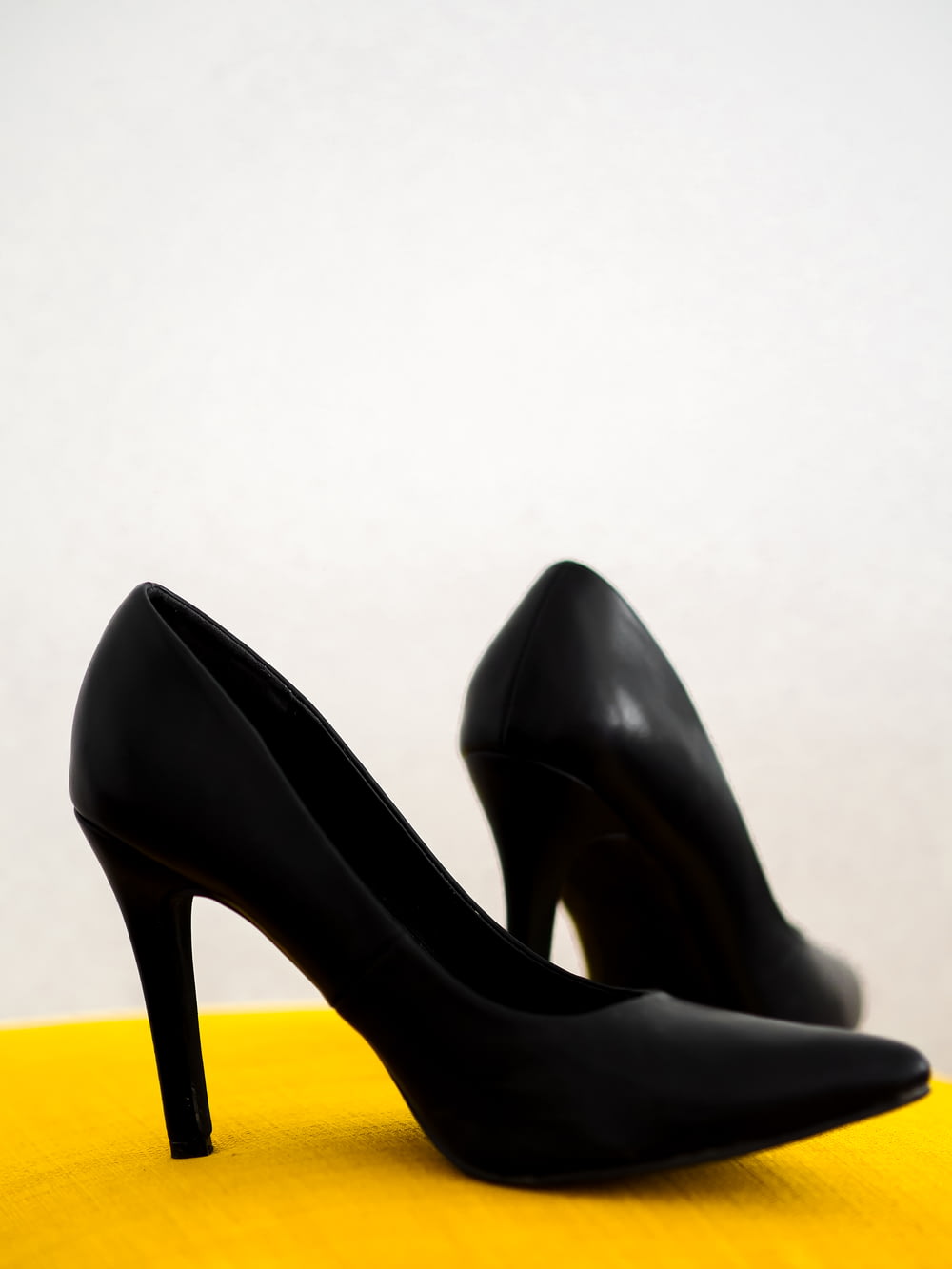 Schuhe mit schwarzen Lederabsätzen auf gelbem Stuhl